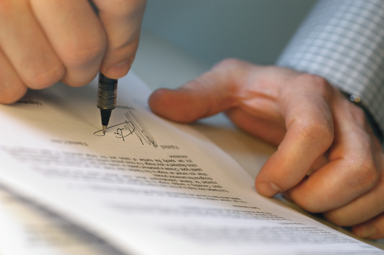 Man's Hands Signing Document --- Image by © Royalty-Free/Corbis