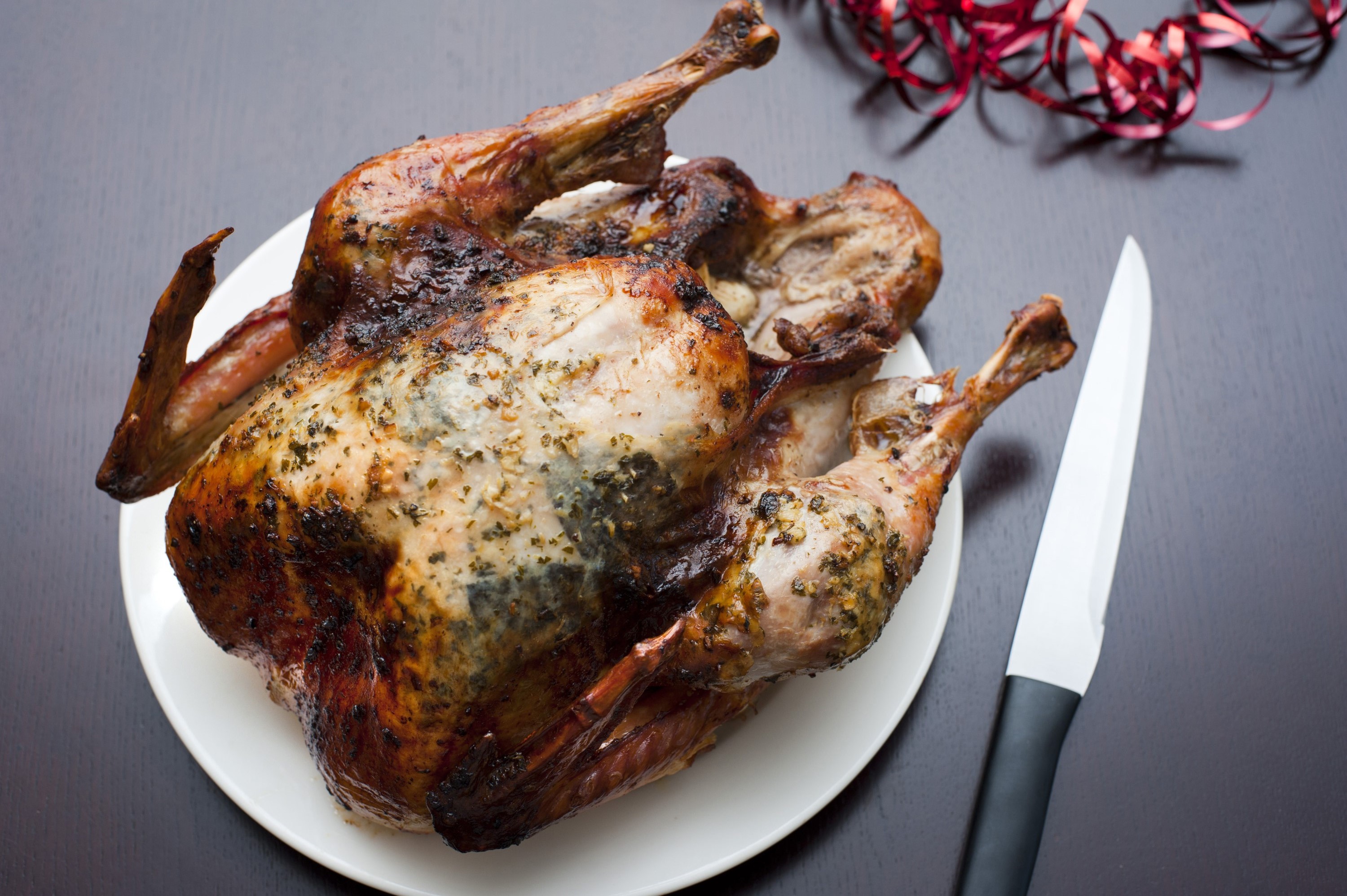 Whole crispy brown roast Christmas or Thanksgiving turkey waiting on a plate to be carved for dinner , overhead view